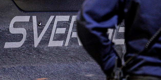 A police officer stands next to a minivan with a bullet hole at a gas station in Fittja, Sweden, where a man was found severely injured in the van after being shot at when taking part in a pro-Kurdish demonstration Saturday, Feb. 13, 2016. At least two shots were fired at the minivan from a car. The police are investigating the shooting. (Johan Nilsson/TT via AP) SWEDEN OUT