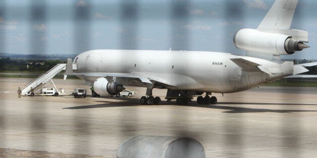 Zimbabwean Armed Soldiers patrol around a United States registered cargo plane at Harare International Airport in Harare, Zimbabwe, Monday, Feb,15.2016. Zimbabwean aviation authorities impounded a U.S.-registered cargo jet after a dead body later believed to be a stowaway and millions of South African rand were found on board, a senior official said Monday. (AP Photo/Tsvangirayi Mukwazhi)
