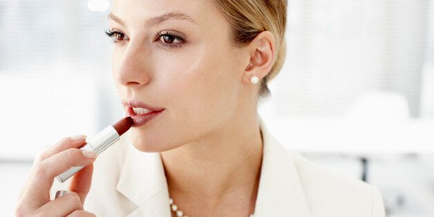 Businesswoman applying lipstick