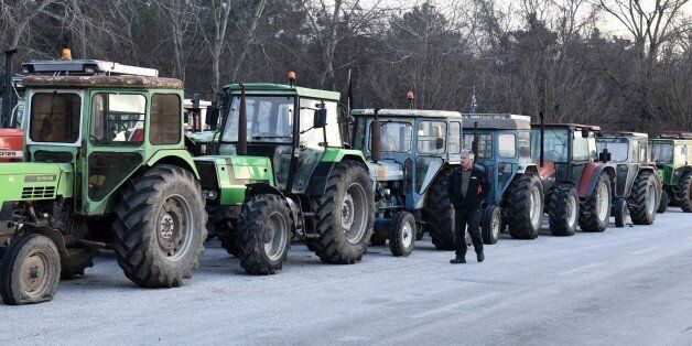 A protesting farmer walks next to parked tractors during a blockade in the northern Greek village of Promahonas village at the customs of the Greek-Bulgarian borderline on Monday, Jan. 25, 2016. Greek farmers angry at planned pension and tax reforms have expanded their campaign of blocking highways and closed a border crossing to Bulgaria, leaving dozens of trucks stranded on either side of the border. (AP Photo/Giannis Papanikos)