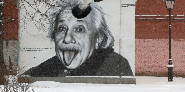 Pigeons fly past a portrait of Albert Einstein painted on a wall in St.Petersburg, Russia, Tuesday, Jan. 12, 2016. Low temperatures caused the two-days of snowfall in St.Petersburg. (AP Photo/Dmitry Lovetsky)