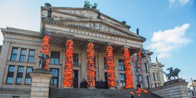 Assistants of Chinese artist Ai Weiwei decorate the columns of Berlin's Konzerthaus concert hall with lifejackets, on February 13, 2016, as part of a temporary installation intended to remind people of the ongoing refugee crisis. The Cinema for Peace gala will be held at the Konzerthaus on February 15, 2016, on the sidelines of the Berlinale Film Festival. / AFP / John MACDOUGALL / RESTRICTED TO EDITORIAL USE - MANDATORY MENTION OF THE ARTIST UPON PUBLICATION - TO ILLUSTRATE THE EVENT AS SPECIFIED IN THE CAPTION (Photo credit should read JOHN MACDOUGALL/AFP/Getty Images)
