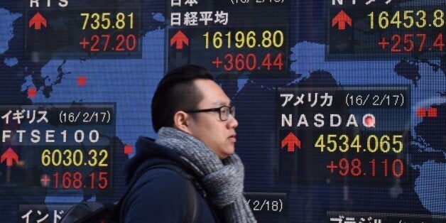 A pedestrian walks past a share prices board showing numbers of the Tokyo Stock Exchange (C, top) in Tokyo on February 18, 2016. Tokyo shares closed more than two percent higher February 18, rebounding from losses the previous day to extend a global rally fuelled by a surge in oil prices. The benchmark Nikkei 225 index at the Tokyo Stock Exchange jumped 2.28 percent, or 360.44 points, to finish at 16,196.80. AFP PHOTO / KAZUHIRO NOGI / AFP / JIJI PRESS / KAZUHIRO NOGI (Photo credit should read KAZUHIRO NOGI/AFP/Getty Images)