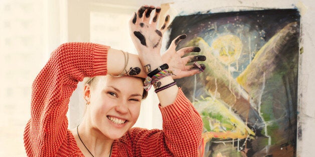 Portrait of beautiful woman artist with quirky expressions and touching her face in home art studio