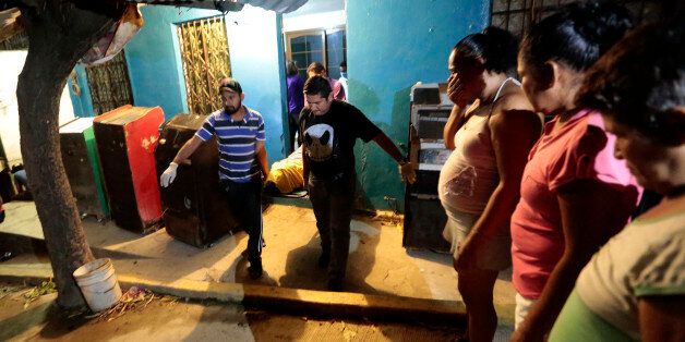 Forensic personnel carry the body of a murdered man cry at Las Cruces neighbourhood in Acapulco, Guerrero state, Mexico on January 21, 2016. Guerrero is one of Mexico's poorest and most violent states, where a lucrative drug trade has flourished. / AFP / Pedro Pardo (Photo credit should read PEDRO PARDO/AFP/Getty Images)