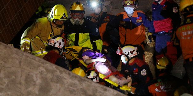 A female is rescued from a collapsed building complex after an early morning earthquake in Tainan, Taiwan, Saturday, Feb. 6, 2016. A 6.4-magnitude earthquake struck southern Taiwan early Saturday, toppling at least one high-rise residential building and trapping people inside. (AP Photo/Wally Santana)