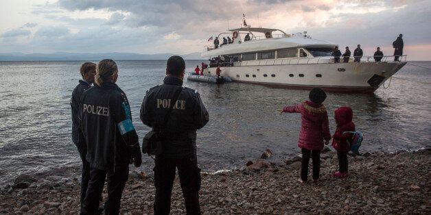 Frontex security personnel watch refugees and migrants disembarking from a yacht on the Greek island of Lesbos, after crossing a part of the Aegean sea from Turkey's coast, early in the morning Saturday, Nov. 21, 2015. Most nations along Europe's refugee corridor, except Greece, abruptly shut their borders Thursday to those not coming from war-torn countries such as Syria, Afghanistan or Iraq, leaving thousands desperately seeking a better life in the continent stranded at Balkan border crossing