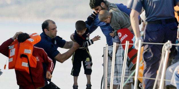 A father gives his son to a coast guard officer, second left, as he disembarks from a vessel at the port of Mitylene after being picked up by the Greek coast guard near the northeast Greek island of Lesvos on Wednesday, June 17, 2015. Around 100,000 migrants have entered Europe so far this year as Italy and Greece have borne the brunt of the surge with many more migrants expected to arrive from June through to September. (AP Photo/Thanassis Stavrakis)