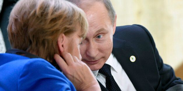 Russian President Vladimir Putin (R) speaks with German Chancellor Angela Merkel during the opening day of the World Climate Change Conference 2015 (COP21), on November 30, 2015 at Le Bourget, on the outskirts of the French capital Paris. World leaders opened an historic summit in the French capital with 'the hope of all of humanity' laid on their shoulders as they sought a deal to tame calamitous climate change. AFP PHOTO / ALAIN JOCARD / AFP / ALAIN JOCARD (Photo credit should read A