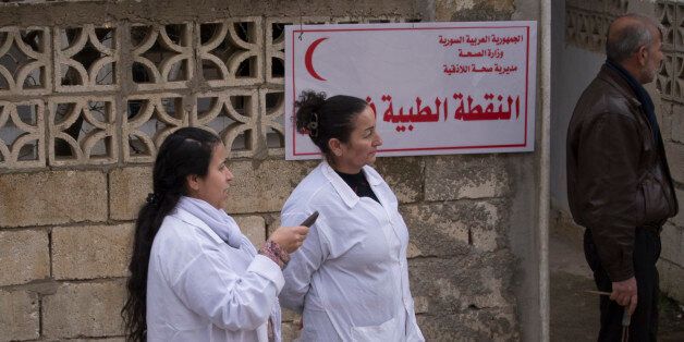 Syrian medics stand at a building in Salma, Syria, Friday, Jan. 22, 2016. Syrian government forces relying on Russian air cover have recently seized Salma, located in Syria's province of Lattakia, from militants. The Syrian government offensive has given Assad a stronger hand going into peace talks with the opposition that are planned for next week in Switzerland. (AP Photo/Vladimir Isachenkov)
