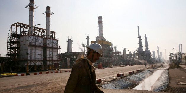 FILE - In this Dec. 22, 2014 file photo, an Iranian oil worker makes his way through Tehran's oil refinery south of the capital Tehran, Iran. Across a Mideast fueled by oil production, low global prices have some countries running on empty and scrambling to cover shortfalls, even as more regional crude is on tap to enter the market.(AP Photo/Vahid Salemi, File)
