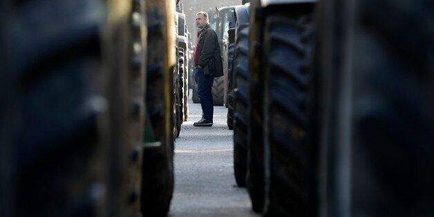 A man checks the tractors which were parked by protesting farmers in the northern Greek village of Promachonas village at the customs of the Greek-Bulgarian borderline on Thursday, Jan. 21, 2016. Farmers prepare to use their tractors to block key highways in northern Greece, to protest drastic new income cuts under planned pension reforms by the radical left-led government. (AP Photo/Thanassis Stavrakis)