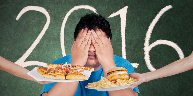 Portrait of overweight person rejects fast food and close his eye with numbers 2016 on the blackboard