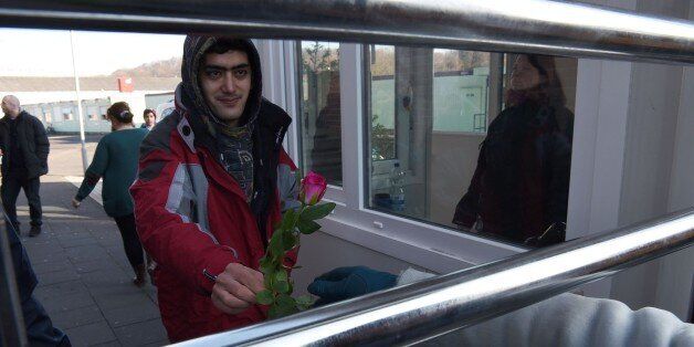 A refugee from Afghanistan is given a flower in front of a refugee camp during an action of German women demonstrating against violence in Cologne, western Germany on January 22, 2016.Hundreds of women were groped and robbed in a throng of mostly Arab and North African men during New Year's festivities in Cologne. German authorities said that nearly all the suspects in a rash of New Year's Eve violence against women in Cologne were 'of foreign origin', as foreigners came under attack amid surging tensions. / AFP / PATRIK STOLLARZ (Photo credit should read PATRIK STOLLARZ/AFP/Getty Images)