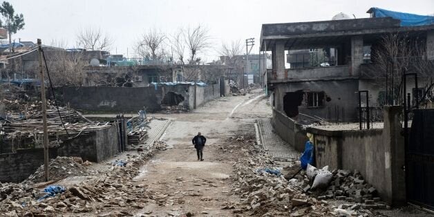 TOPSHOT - A man walks along a road damaged in the fighting between government troops and separatist Kurdistan Workers' Party (PKK) fighters, in the Kurdish town of Silopi, in southeastern Turkey, near the border with Iraq on January 19, 2016. Turkey is waging an all-out offensive against the separatist Kurdistan Workers' Party (PKK), with military operations backed by curfews aimed at flushing out rebels from several southeastern urban centres. / AFP / ILYAS AKENGIN (Photo credit should read ILYAS AKENGIN/AFP/Getty Images)