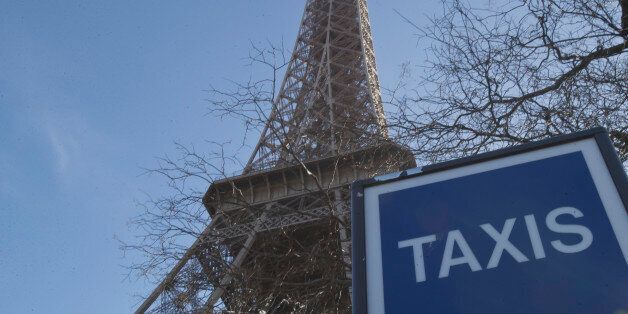 A taxi sign next to the Eiffel Tower in Paris, Wednesday, Feb. 12, 2014. Taxi drivers protested against competition from tourist transport vehicles. (AP Photo/Michel Euler)