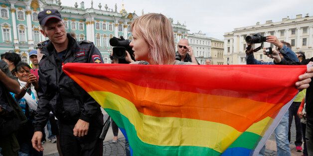 A gay rights activist stands with a rainbow flag, in front of journalists, during a protesting picket at Dvortsovaya (Palace) Square in St.Petersburg, Russia, Sunday, Aug. 2, 2015. Several gay rights activists stood protesting against gay rights violation at Palace square where paratroopers celebrated Paratroopers' Day. (AP Photo/Dmitry Lovetsky)