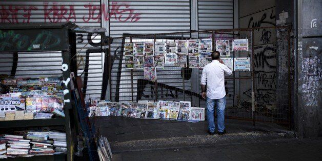 A man reads newspaper headlines at a kiosk in the central Athens on July 20, 2015. Greek banks reopened on July 20 after a shutdown lasting three weeks imposed by the government to avert a crash in the banking system over the country's debt crisis. However, capital controls in force since June 29 remain in place, although a daily cash withdrawal limit of 60 euros ($65.03) has now been relaxed to a weekly restriction of 420 euros. AFP PHOTO / ANGELOS TZORTZINIS (Photo credit should read ANGELOS TZORTZINIS/AFP/Getty Images)
