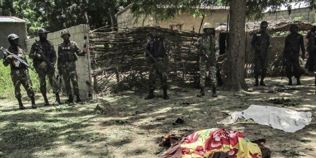 Cameroon security forces look on while a victim of a twin suicide attack lies on the ground in the extreme north village of Kolofata on September 13, 2015. Two suicide bombers killed seven people on September 13 in attacks in the northern Cameroon town of Kolofata, near the border with Nigeria, an army official said. 'According to initial information, nine people have died and 20 were injured,' he said, giving a toll that included the bombers. Kolofata is near Kerawa where at least 20 people died in two suicide attacks on September 3. AFP PHOTO / STRINGER (Photo credit should read -/AFP/Getty Images)
