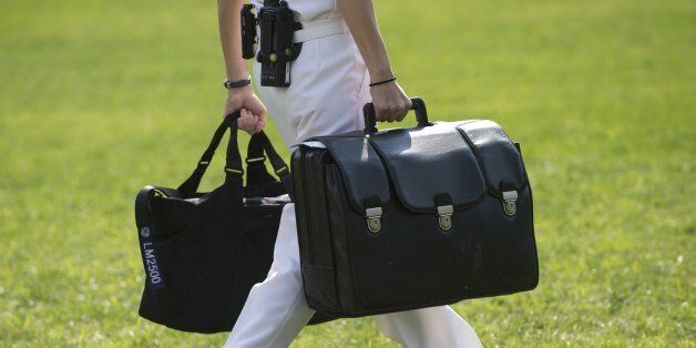 A White House military aide and member of the US Navy carries a briefcase known as the 'football,' containing emergency nuclear weapon codes, as US President Barack Obama departs on Marine One from the South Lawn of the White House in Washington, DC, September 30, 2012. AFP PHOTO / Saul LOEB (Photo credit should read SAUL LOEB/AFP/GettyImages)