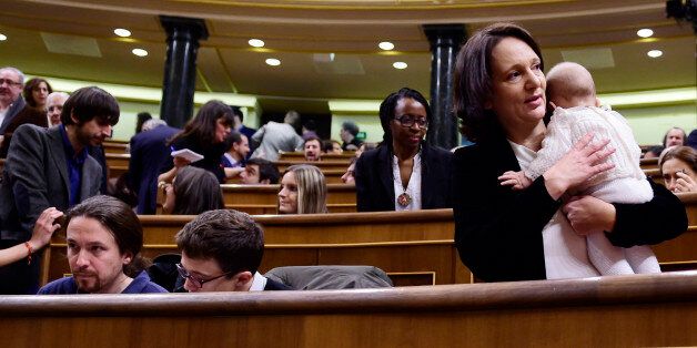 Left wing party Podemos' deputy Carolina Bescansa (R) holds her baby past Podemos' leader Pablo Iglesias (L) and Podemos' member Inigo Errejon during the constitution of the Congress, at the Palacio de las Cortes in Madrid on January 13, 2016. Spain's parliament holds its first session today, with lawmakers from four conflicting main parties taking their seats at a time of political turmoil intensified by a resurgent secessionist threat in the Catalonia region. AFP PHOTO/ PIERRE-PHILIPPE MARCOU / AFP / PIERRE-PHILIPPE MARCOU (Photo credit should read PIERRE-PHILIPPE MARCOU/AFP/Getty Images)