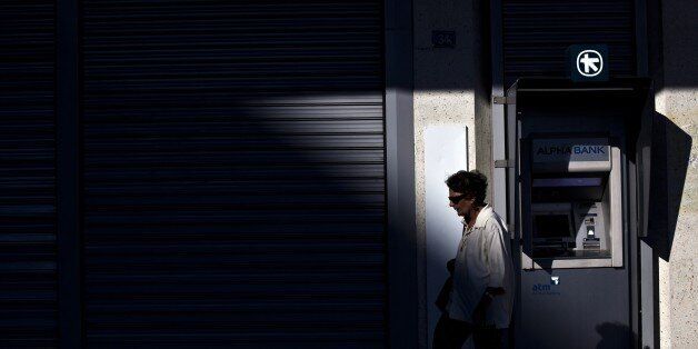 A woman walks in front of the ATM of an Alpha Bank branch in Athens on July 19, 2015. Banks are set to reopen Monday after a three-week shutdown estimated to have cost the economy some 3.0 billion euros ($3.3 billion) in market shortages and export disruption. AFP PHOTO / ANGELOS TZORTZINIS (Photo credit should read ANGELOS TZORTZINIS/AFP/Getty Images)