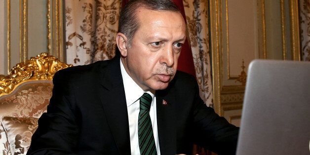 Turkey's President Recep Tayyip Erdogan checks to vote for photos produced in 2015 by semi-offcial Anadolu agency photographers, in Istanbul, late Friday, Dec. 25, 2015. (Basin Bulbul, Presidential Press Service Pool via AP)