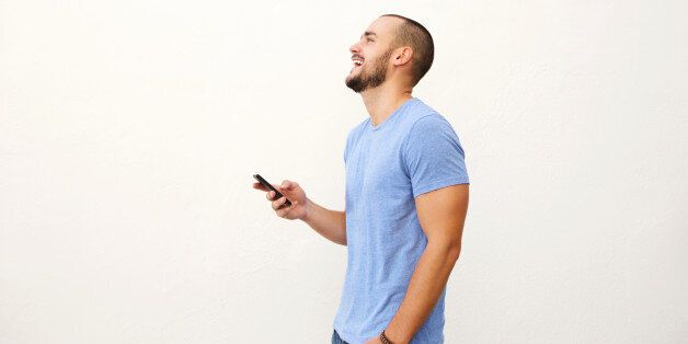 Cheerful young man walking with mobile phone against white background