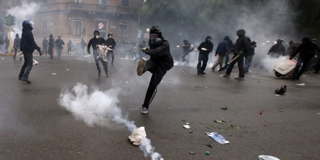 FILE - A demonstrators kicks a teargas canister as clashes broke out with Italian Policemen during a protest against the Expo 2015 fair in Milan, Italy, Friday, May 1, 2015. (AP Photo/Luca Bruno, File)