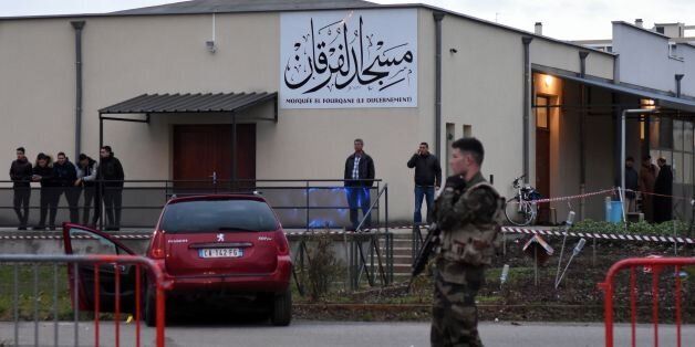 French police officers and soldiers stand near a red car in front of the mosque of Valence, southeastern France, on January 1, 2016, after a soldier guarding the mosque shot and wounded a driver who rammed him with a car. Police said the driver deliberately drove his Peugeot into the soldier in the southeastern city of Valence. The impact of the car left the soldier with injuries to his knee and shin. Police said the driver's motive remained unclear. / AFP / PATRI