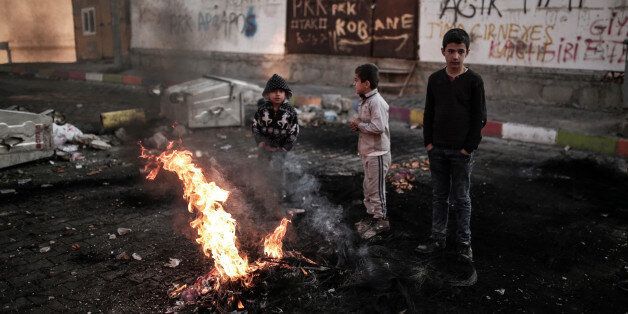 In this photo taken on Monday, Dec. 21, 2015, children stand next to the barricades set up by the militants of the Kurdistan Workers' Party, or PKK, in Sirnak, Turkey. Tens of thousands of civilians in southeast Turkey are caught in the middle as government forces and Kurdish militants battle in urban areas. Turkish authorities have sent thousands of troops and tanks to crush pockets of resistance across mainly Kurdish districts where fighters linked to the outlawed Kurdistan Workersâ Party have set up ditches and trenches to keep them at bay.(AP Photo/Cagdas Erdogan)