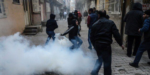 A man starts to throw tear gas as people clash with Turkish police at the Sur district in Diyarbakir, southeastern Turkey, on January 3, 2016. Tensions are running high throughout Turkey's restive southeast as security forces impose curfews in several towns including Cizre in a bid to root out Kurdistan Workers' Party (PKK) rebels from urban centres. / AFP / ILYAS AKENGIN (Photo credit should read ILYAS AKENGIN/AFP/Getty Images)