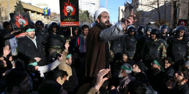 Surrounded by policemen, a Muslim cleric addresses a crowd during a demonstration to denounce the execution of Saudi Shiite Sheikh Nimr al-Nimr, seen in poster, in front of the Saudi embassy in Tehran, Iran, Sunday, Jan. 3, 2016. Saudi Arabia announced the execution of al-Nimr on Saturday along with 46 others. Al-Nimr was a central figure in protests by Saudi Arabia's Shiite minority until his arrest in 2012, and his execution drew condemnation from Shiites across the region. (AP Photo/Vahid Salemi)