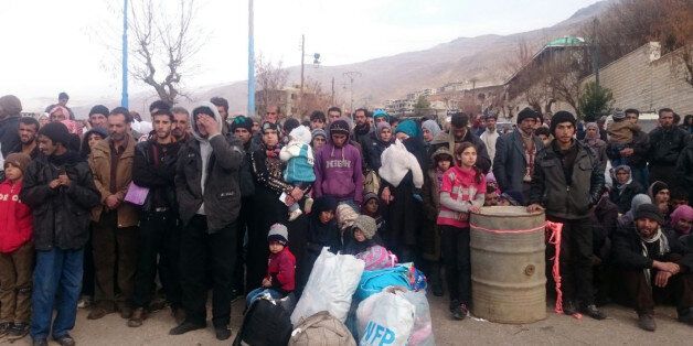 Syrians wait for the arrival of an aid convoy on January 11, 2016 in the besieged town of Madaya as part of a landmark six-month deal reached in September for an end to hostilities in those areas in exchange for humanitarian assistance.Forty-four trucks operated by the International Committee of the Red Cross, the Syrian Red Crescent, the United Nations and World Food Programme left from Damascus to enter Madaya, where more than two dozen people are reported to have starved to death. / AFP / STR