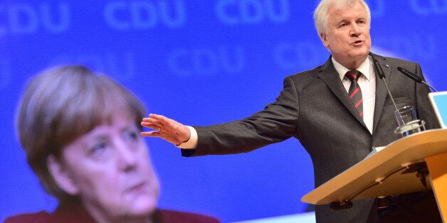 KARLSRUHE, GERMANY - DECEMBER 15: Horst Seehofer, head of Bavarian Christian Democrats (CSU) and Governeur of Bavaria speaks while the face of German Chancellor and Chairwoman of the German Christian Democrats (CDU) Angela Merkel is seen on the screen behind him at the annual CDU federal congress on December 15, 2015 in Karlsruhe, Germany. The CDU is meeting following a dramatic year in which Germany admitted approximately one million migrants and refugees under an open-door policy spearheaded by Merkel. A growing number of CDU members think Merkel has gone too far and see the influx as a burdensome challenge that should have been capped sooner. (Photo by Thomas Lohnes/Getty Images)
