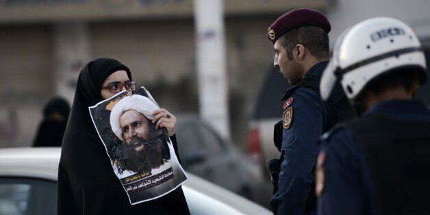 TOPSHOT - A Bahraini woman holds a poster of prominent Shiite Muslim cleric Nimr al-Nimr during clashes with riot police following a protest against the execution Nimr of by Saudi authorities, in the village of Daih, west of the capital Manama on January 4, 2016. Sunni-ruled Saudi Arabia severed diplomatic ties with Shiite-dominated Iran, its long-time regional rival, after angry demonstrators attacked the Saudi embassy in Tehran and its consulate following Nimr's execution. AFP PHOTO / MOHAMMED AL-SHAIKH / AFP / MOHAMMED AL-SHAIKH (Photo credit should read MOHAMMED AL-SHAIKH/AFP/Getty Images)