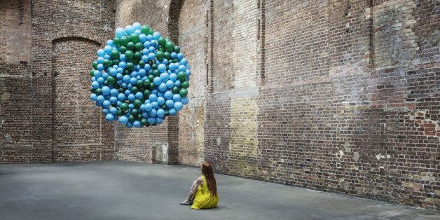 Woman in warehouse with globe made of balloons