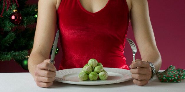Female in Christmas outfit eating brussels sprouts