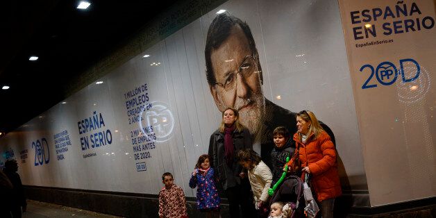 EDS NOTE : SPANISH LAW REQUIRES THAT THE FACES OF MINORS ARE MASKED IN PUBLICATIONS WITHIN SPAIN People pose for a snapshot in front of a photograph of Popular Party leader and current Prime Minister of Spain Mariano Rajoy and with a slogan reading in Spanish 'Spain: Seriously', in Madrid, Saturday, Dec. 19, 2015. The Spanish general elections will be held on Sunday, Dec. 20. (AP Photo/Daniel Ochoa de Olza)