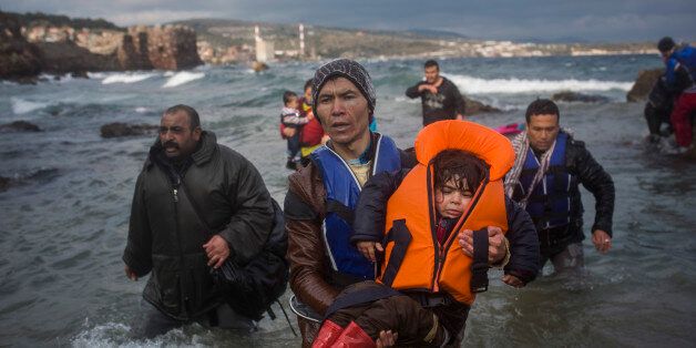 Refugees and migrants make their way out of the sea, as their boat, on which they crossed a part of the Aegean sea from Turkey, hit on rocks on the Greek island of Lesbos, on Saturday, Dec. 12, 2015. Any link between extremism and the thousands of people fleeing violence in Syria and elsewhere is false, a top European human rights official said Friday, noting that those who have perpetrated recent attacks in Europe were citizens of European countries.(AP Photo/Santi Palacios)