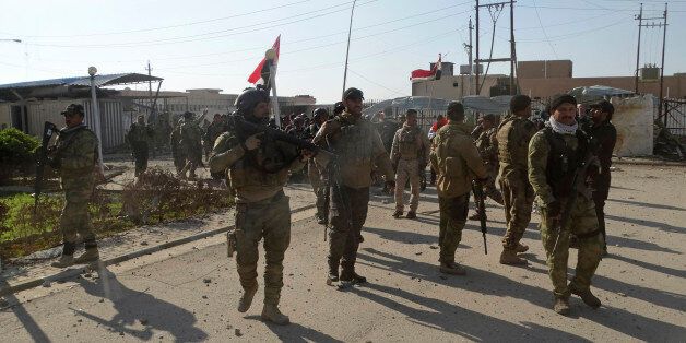 Iraqi security forces enter the government complex in central Ramadi, 70 miles (115 kilometers) west of Baghdad, Iraq, Monday, Dec. 28, 2015. Iraqi military forces on Monday retook a strategic government complex in the city of Ramadi from Islamic State militants who have occupied the city since May. (AP Photo/Osama Sami)