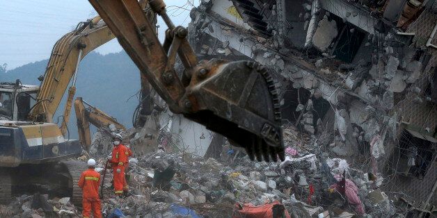 Rescuers search for potential survivors near a damaged building following a landslide at an industrial park in Shenzhen, in south China's Guangdong province, Tuesday, Dec. 22, 2015. Authorities blamed an enormous, man-made mountain of soil and waste for the collapse of nearly three dozen buildings in southern China's most prominent manufacturing city. (AP Photo/Andy Wong)