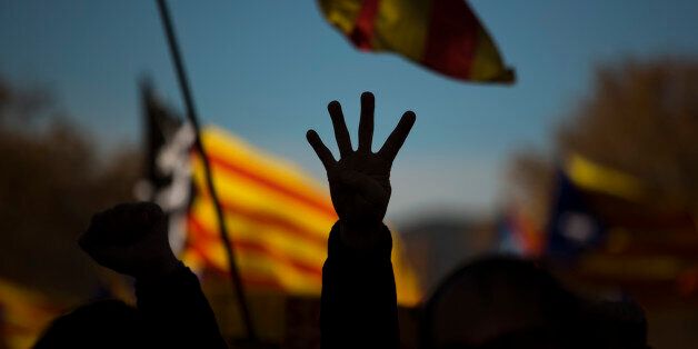 A pro Independence demonstrator gestures - four fingers symbolizing the four bars of the Catalonian flag, during a demonstrations to show public support for the Parliament of Catalonia, in Barcelona, Spain, Sunday, Nov. 22, 2015. Prime Minister Mariano Rajoy made his first visit to the regional capital of Catalonia on Saturday following his administration's legal push to halt an effort secessionist regional parties to declare independence from Spain by 2017. (AP Photo/Emilio Morenatti)