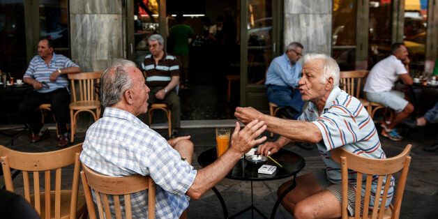 Local residents gesticulate as they speak to one another at a cafe terrace in Athens, Greece, on Friday, July 17, 2015. Germany's Parliament is set to ratify bridge financing and the start of talks for a three-year rescue plan. Photographer: Yorgos Karahalis/Bloomberg via Getty Images