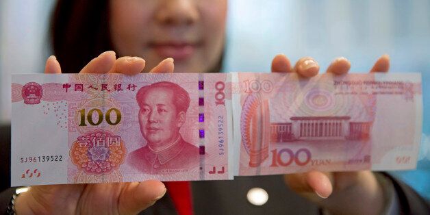 A staff member displays the new version of the 100-yuan RMB banknotes (US 15.7 dollars) to photographers at the Bank of China Tower in Hong Kong, Thursday, Nov. 12, 2015. China released Thursday a new version of the 100-yuan bill, which bears a golden
