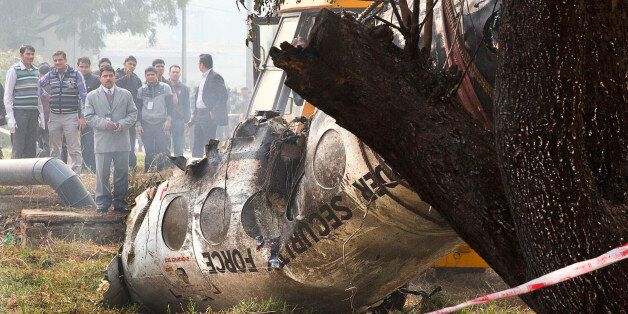 Indian investigators look at the remains of a small Indian paramilitary plane that crashed outside the airport in New Delhi, India, Tuesday, Dec. 22, 2015. An inquiry has been ordered to determine that cause of the crash of the Super King plane belonging to India's Border Security Force, Junior Aviation Minister Mahesh Sharma told reporters. (AP Photo/Manish Swarup)