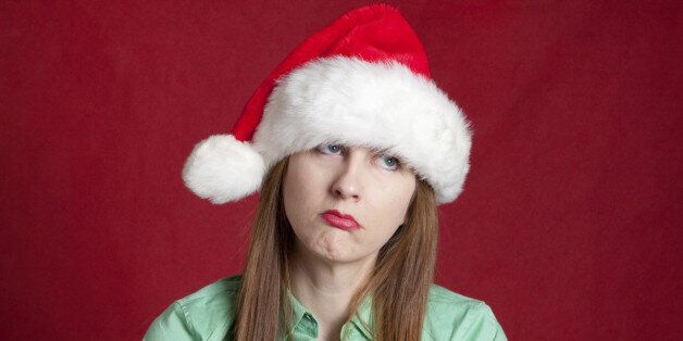 A woman wearing a Santa hat and feeling depressed about Christmas.