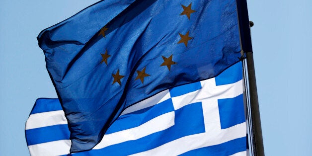 A European Union (EU) flag and a Greek national flag fly in central Athens, Greece, on Saturday, July 18, 2015. Greek banks will reopen on Monday as Prime Minister Alexis Tsipras rebuilds his government to shore up support for a bailout agreed with the countrys creditors. Photographer: Matthew Lloyd/Bloomberg via Getty Images