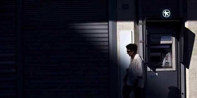 A woman walks in front of the ATM of an Alpha Bank branch in Athens on July 19, 2015. Banks are set to reopen Monday after a three-week shutdown estimated to have cost the economy some 3.0 billion euros ($3.3 billion) in market shortages and export disruption. AFP PHOTO / ANGELOS TZORTZINIS (Photo credit should read ANGELOS TZORTZINIS/AFP/Getty Images)