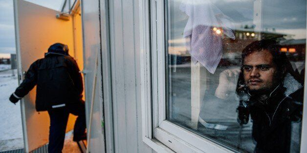 A refugee looks through a window as he speaks on the phone in the sleeping facilities at the arrival centre for refugees near the town on Kirkenes in northern Norway close to the border with Russia on November 11, 2015. An increasingly popular route for migrants across Russia and into Norway has Oslo angered and worried as winter approaches, as commentators suspect Moscow of deliberately creating problems for its neighbouring NATO member. AFP PHOTO / JONATHAN NACKSTRAND (Photo credit should read JONATHAN NACKSTRAND/AFP/Getty Images)